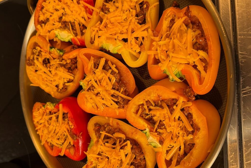 Bell peppers stuffed with sloppy joe ground beef filling and topped with shredded cheddar cheese before baking