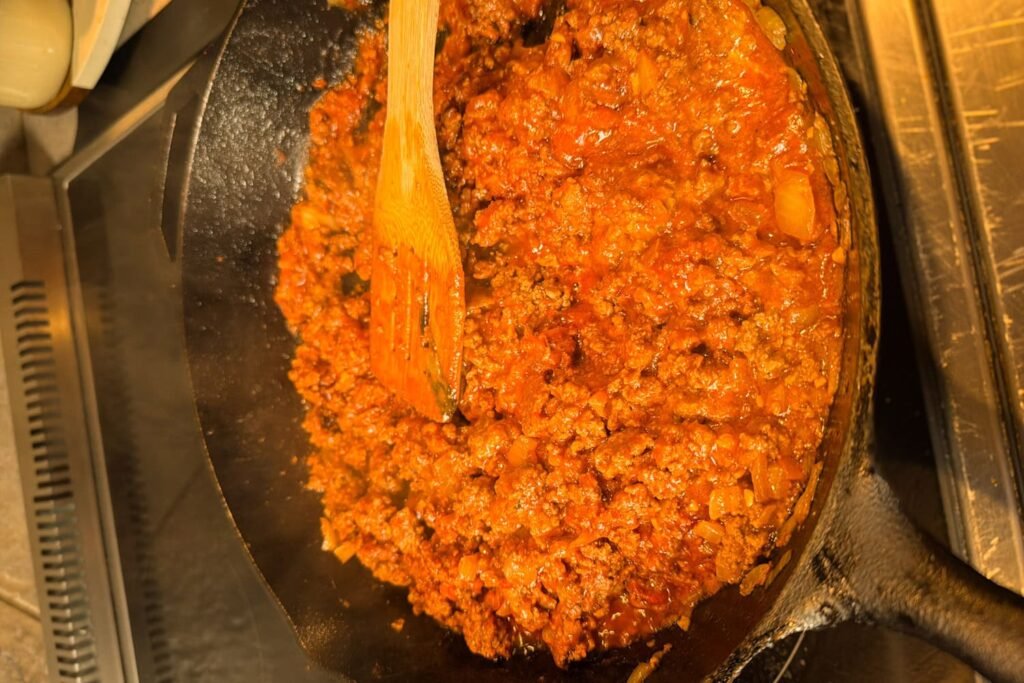 Ground beef and diced onions cooking in a skillet for sloppy Joe stuffed peppers