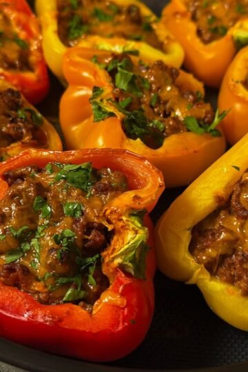 Sloppy Joe stuffed bell peppers filled with seasoned ground beef and melted cheddar cheese, topped with fresh parsley.